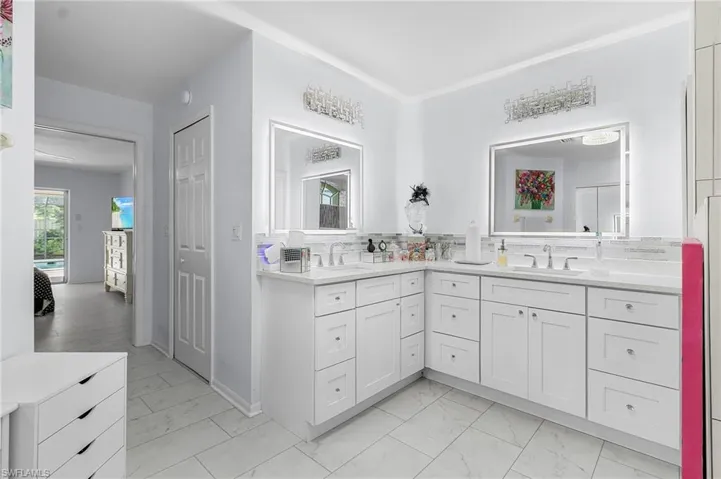 Bathroom with double vanity, luxury vinyl plank flooring, unique tile backsplash, lighted mirror, double vanities and lots of cabinets and a large linen closet and 2 walk in closets