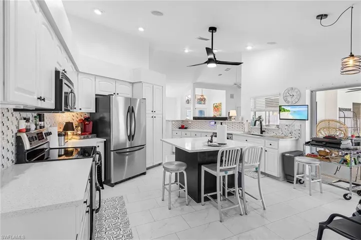 Kitchen with tasteful backsplash, stainless steel appliances, white cabinets, and recessed lighting and black stainless steel farm sink, new dishwasher and sliders to the pool area as well as a pass thru window over the sink