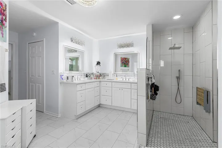 Bathroom featuring walk in shower, double vanity, and luxury vinyl plank flooring, full tile walk or roll in shower, shower stow away seat, multiple shower heads,