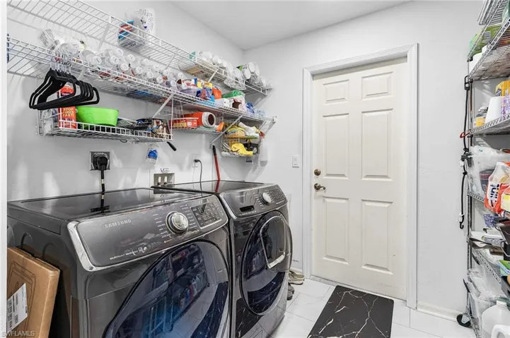 Washroom with newer washing machine and dryer and luxury vinyl flooring and storage shelving and door to the garage
