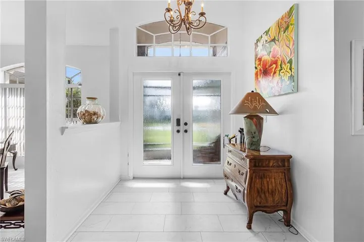 Impact front french doors , and screened in front porch (enjoy the river breezes) foyer featuring a chandelier