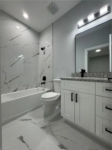 Full bathroom featuring toilet, tiled shower / bath, and vanity