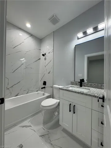 Full bathroom with toilet, vanity, and tiled shower / bath