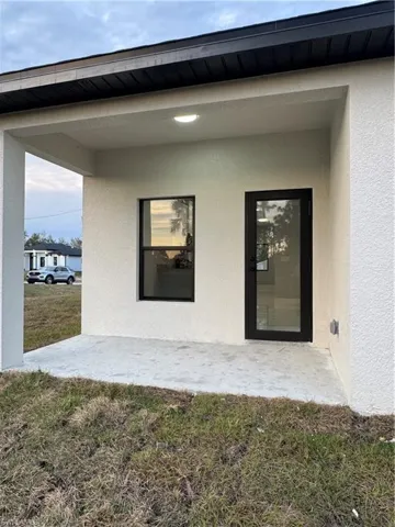 Doorway to property featuring a lawn and a patio area