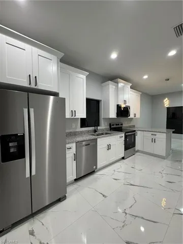 Kitchen featuring white cabinetry, dishwasher, refrigerator, stove, and hanging light fixtures