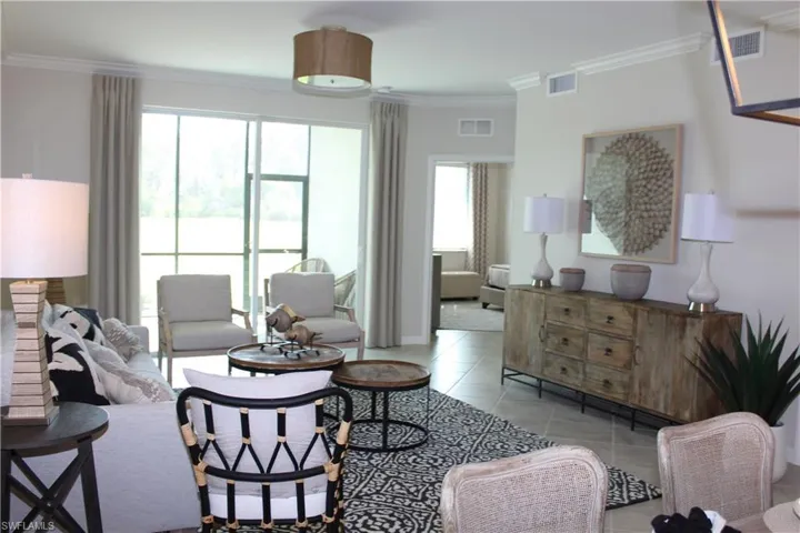 Living area featuring light tile patterned floors, ornamental molding, healthy amount of natural light, and baseboards