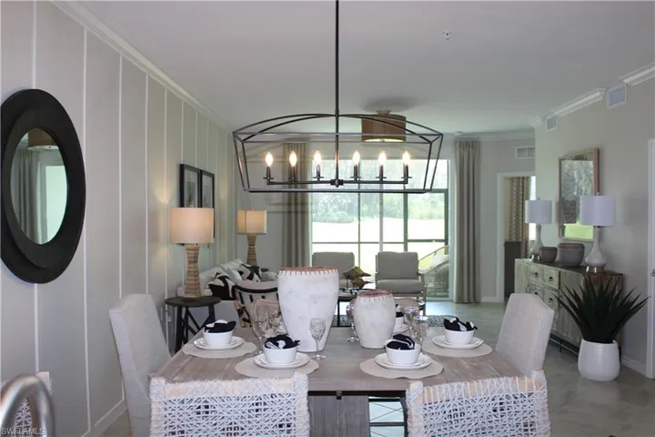 Dining space with a chandelier, crown molding, baseboards, and tile patterned flooring