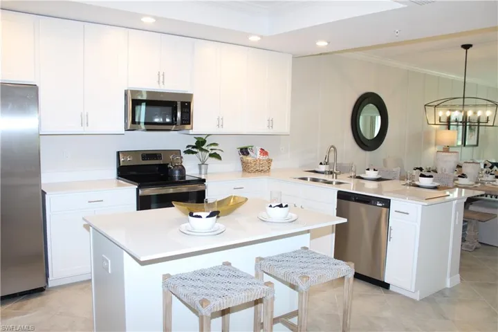 Kitchen with appliances with stainless steel finishes, a sink, ornamental molding, a peninsula, and a chandelier