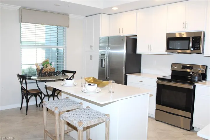 Kitchen with appliances with stainless steel finishes, light tile patterned flooring, light countertops, ornamental molding, and recessed lighting