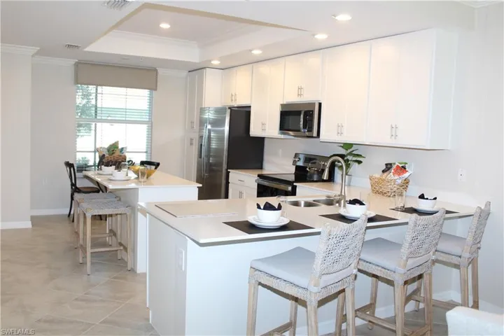 Kitchen featuring stainless steel appliances, ornamental molding, recessed lighting, a sink, and a tray ceiling