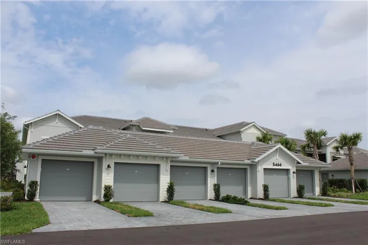 Townhome / multi-family property with a tiled roof, community garages, and stucco siding