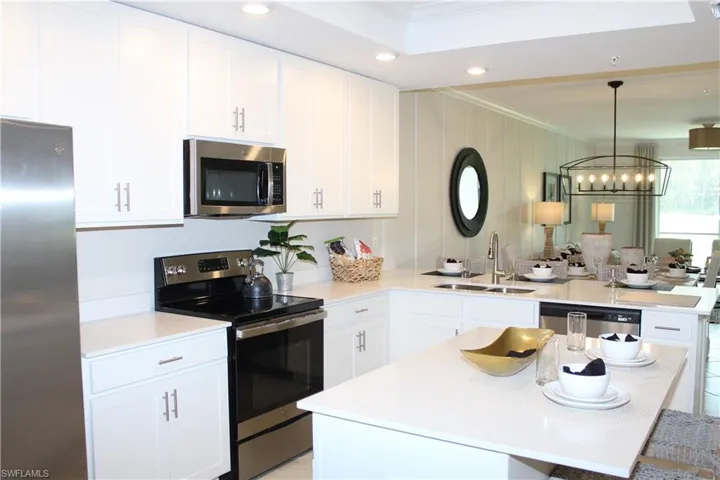 Kitchen featuring stainless steel appliances, a sink, crown molding, a chandelier, and a peninsula