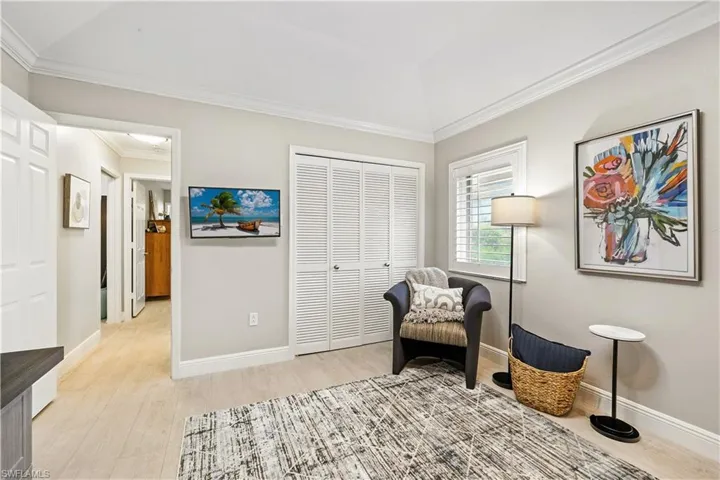 Sitting room with ornamental molding and light wood finished floors