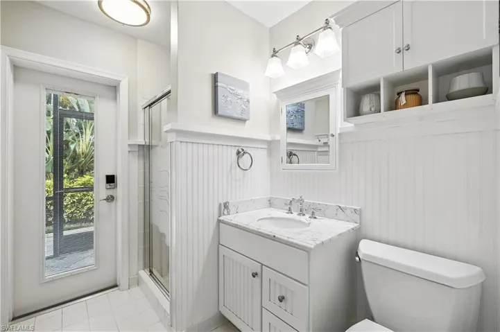 Full bath featuring vanity, a shower stall, light tile patterned floors, and a wainscoted wall