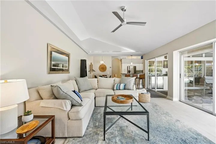 Living room featuring wood finished floors, arched walkways, a ceiling fan, and vaulted ceiling