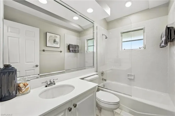 Bathroom featuring combined bath / shower with glass door, vanity, and recessed lighting