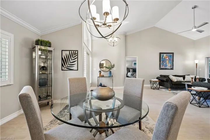 Dining area with crown molding, plenty of natural light, a ceiling fan, light wood-type flooring, and a chandelier