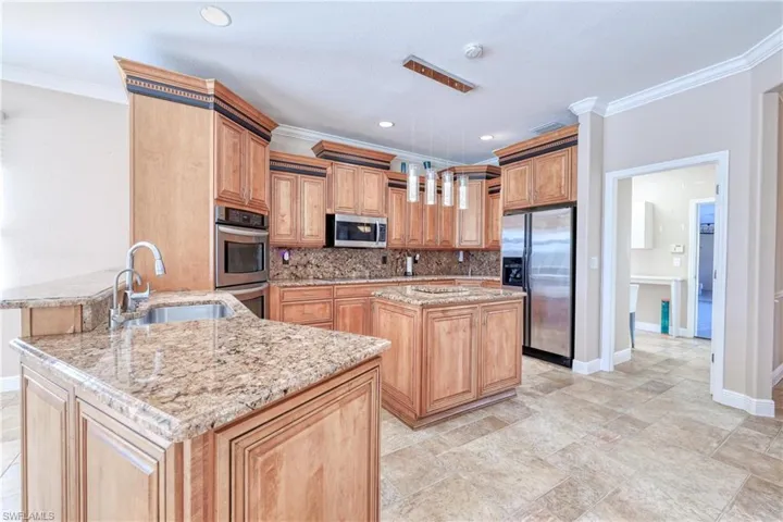 Kitchen with sink, kitchen peninsula, a kitchen island, stainless steel appliances, and decorative backsplash