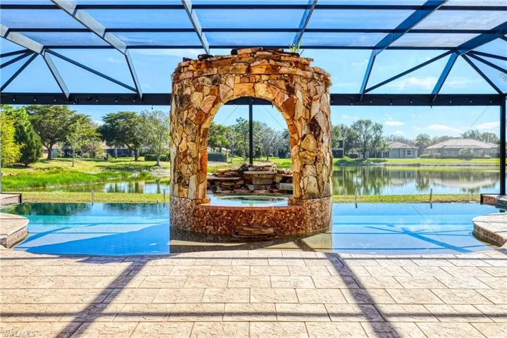 View of swimming pool featuring a water view, an in ground hot tub, a lanai, and a patio area