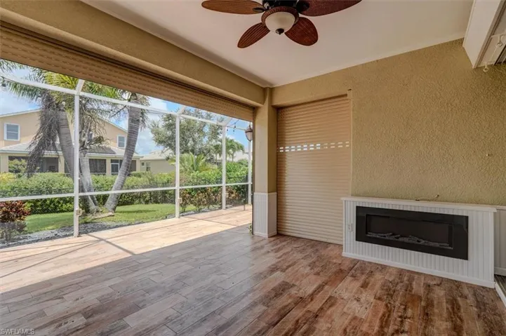 Unfurnished sunroom featuring ceiling fan with digital fireplace