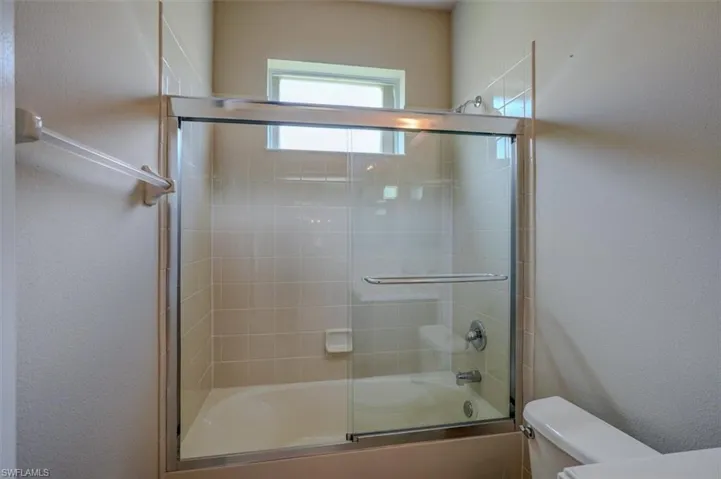 Bathroom featuring toilet and enclosed tub / shower combo