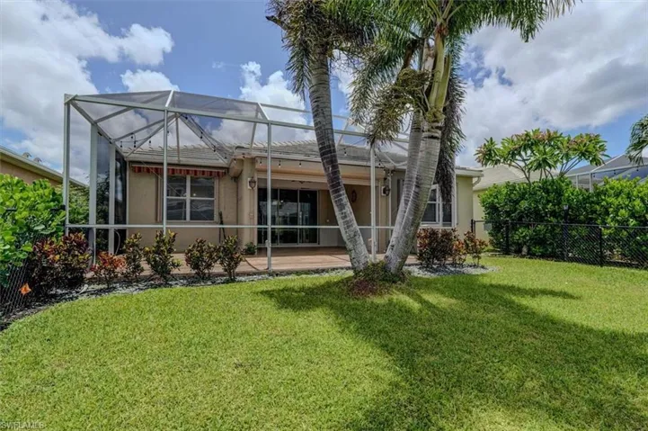Rear view of house with a patio area, a lanai, and a lawn