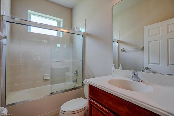 Full bathroom featuring toilet, enclosed tub / shower combo, and vanity