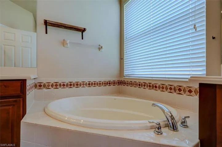 Bathroom featuring tiled tub and plenty of natural light
