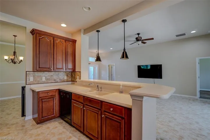 Kitchen with decorative backsplash, pendant lighting, dishwasher, and kitchen peninsula