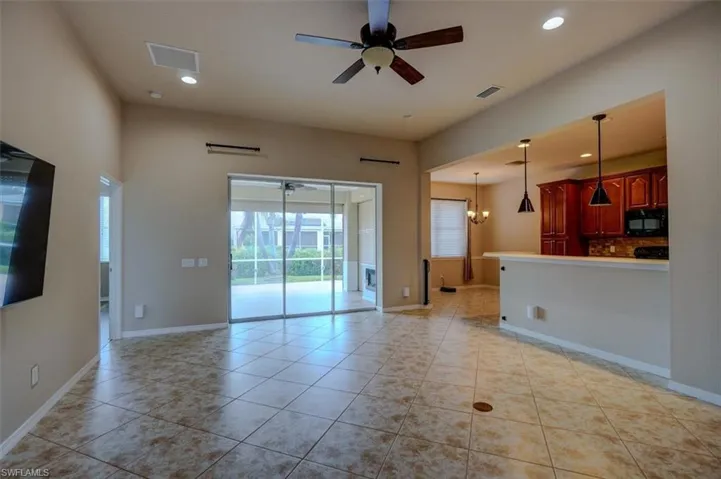 Unfurnished living room with ceiling fan with notable chandelier and light tile patterned floors