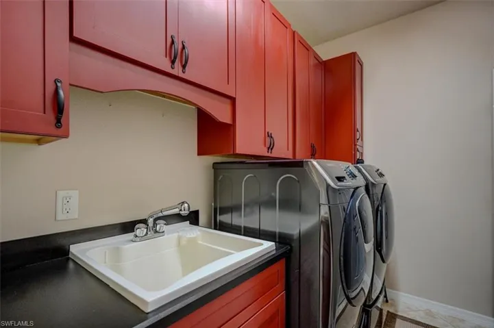 Laundry area featuring cabinets, separate washer and dryer, tile patterned flooring, and sink