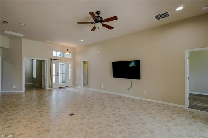 Unfurnished living room featuring a high ceiling, light tile patterned floors, and ceiling fan
