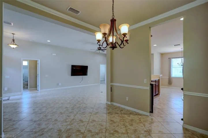 Unfurnished room with light tile patterned flooring and ceiling fan with notable chandelier