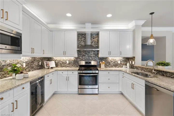 Kitchen featuring stainless steel appliances, light stone countertops, decorative light fixtures, white cabinetry, and recessed lighting