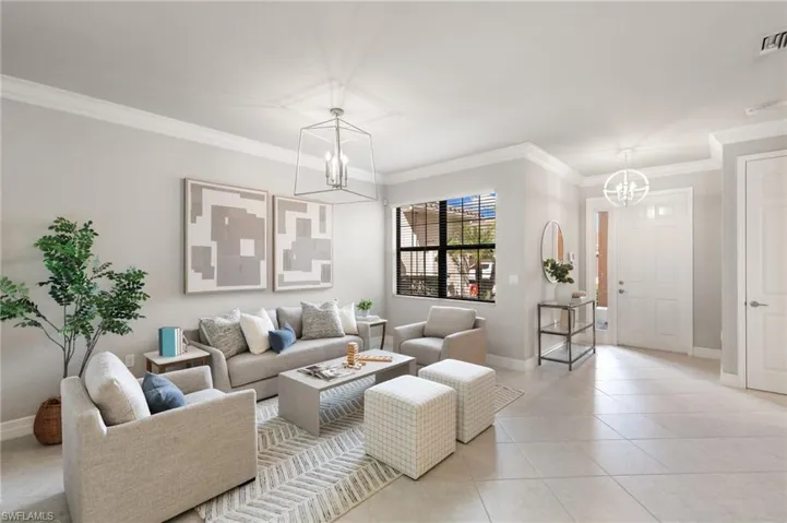 Living room with ornamental molding, a chandelier, and tile patterned floors