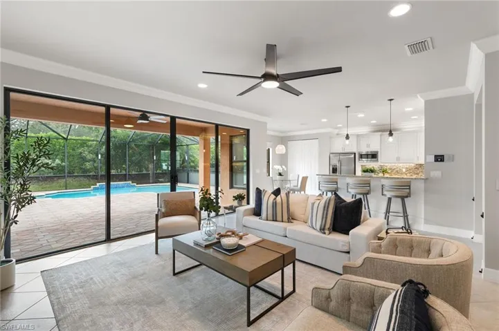 Living area with light tile patterned floors, ornamental molding, recessed lighting, a sunroom, and a ceiling fan