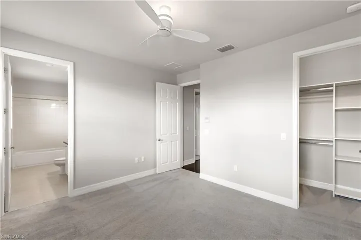 Unfurnished bedroom with carpet floors, a ceiling fan, and connected bathroom