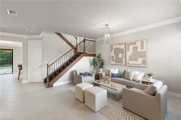 Living room featuring crown molding, stairway, and light tile patterned floors