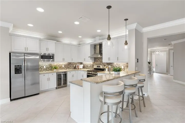 Kitchen with ornamental molding, stainless steel appliances, a peninsula, tasteful backsplash, and a kitchen breakfast bar