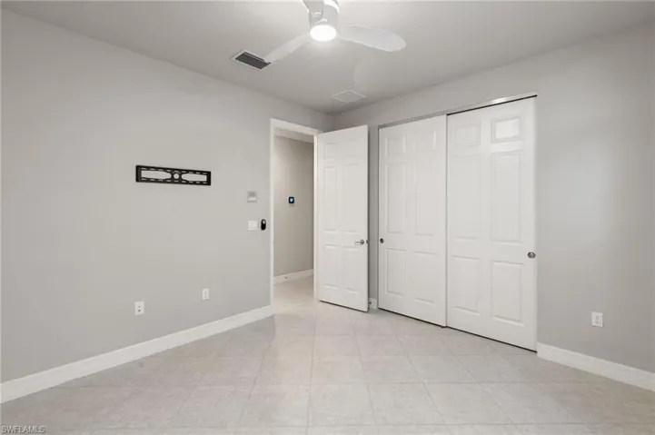 Unfurnished bedroom featuring a ceiling fan, a closet, and light tile patterned flooring