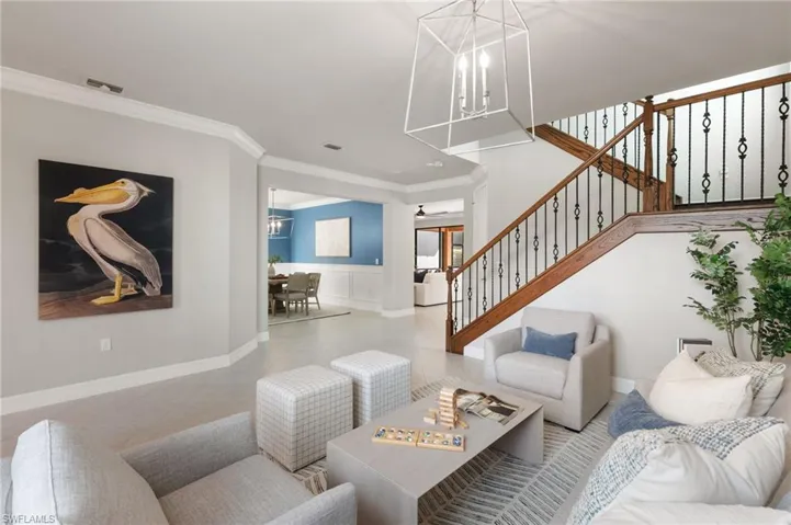 Tiled living room featuring ornamental molding, stairway, and a chandelier