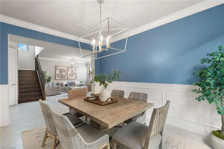 Dining room featuring crown molding, stairs, a decorative wall, wainscoting, and light tile patterned floors