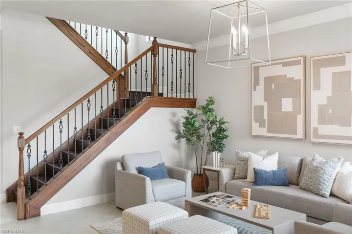 Living area with crown molding, tile patterned floors, a chandelier, and stairway