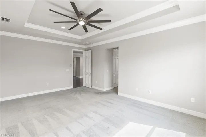 Spare room with a raised ceiling, light colored carpet, crown molding, ceiling fan, and recessed lighting