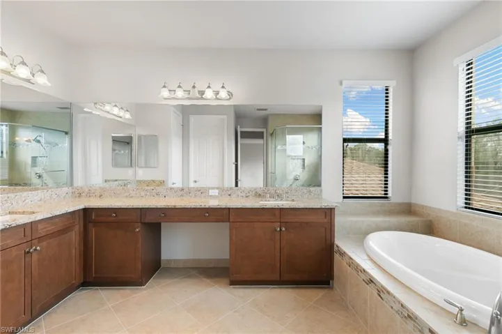 Bathroom featuring a shower stall, vanity, a bath, and light tile patterned flooring