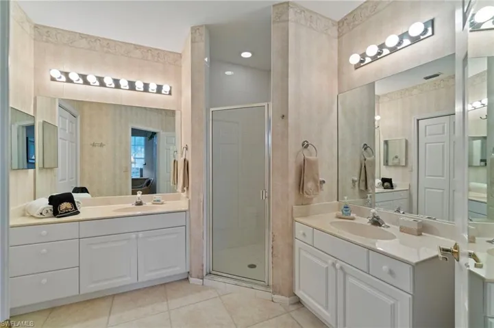 Full bath with light tile patterned floors, a stall shower, two vanities, and recessed lighting