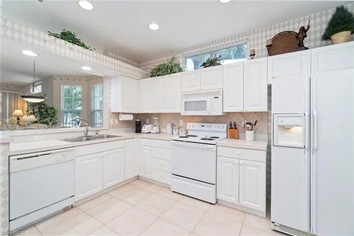 Kitchen with white appliances, decorative backsplash, light countertops, light tile patterned floors, and recessed lighting