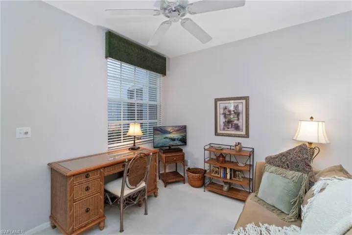 Carpeted office space featuring a ceiling fan