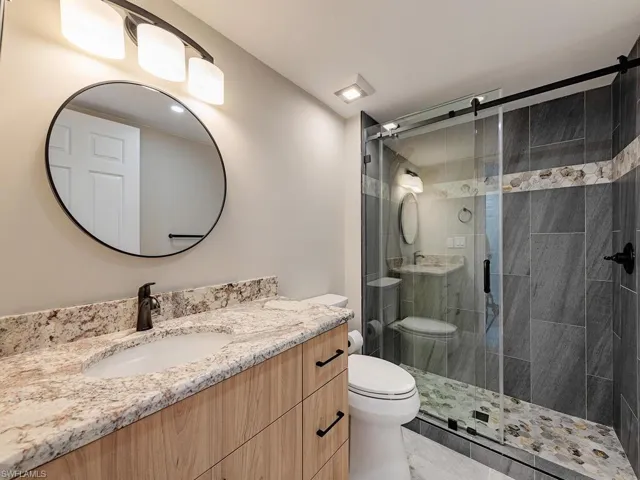 Bathroom featuring vanity, toilet, and an enclosed shower