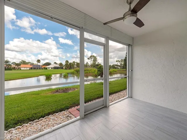 Unfurnished sunroom with a textured wall, a water view, and wood finish floors